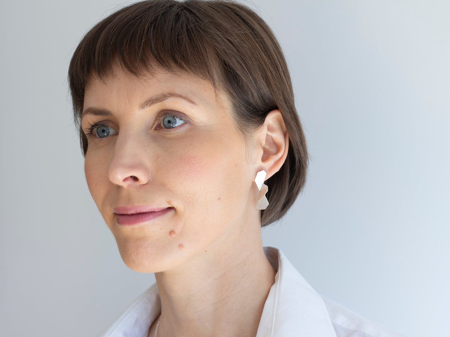 A woman with geometric, sculptural sterling silver earrings
