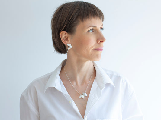 A woman wearing geometric pendant necklace and architectural sterling silver earrings