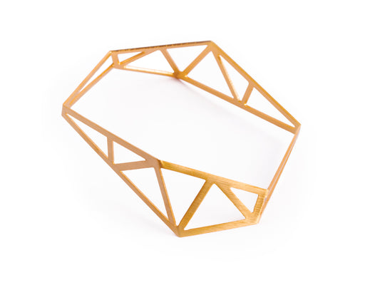 Architecture inspired geometric gold bangle made of folded and cut out metal sheet. Inspired by steel constructions, lightweight, three-dimensional