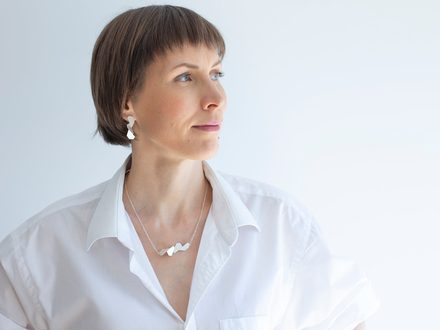 A woman in a white shirt wearing geometric sterling silver jewellery