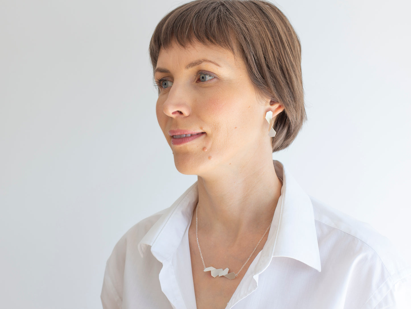 A woman wearing white shirt and sterling silver geometric jewelry