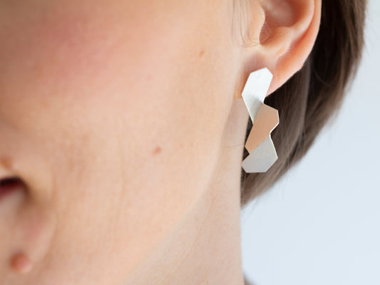 Sculptural folded sterling silver earrings, worn by a model