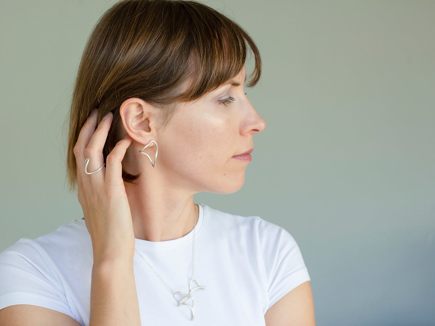 A woman wearing organic shape sterling silver earrings, silver link necklace