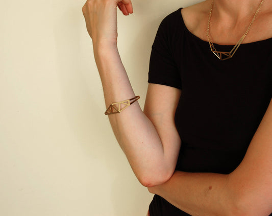 Architecture inspired geometric gold bangle made of folded and cut out metal sheet. Inspired by steel constructions, lightweight, three-dimensional